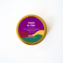 Load image into Gallery viewer, Candle tin labeled 'como la Flor' with colorful label on a white background