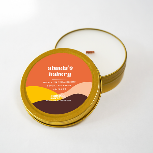 Candle in a tin with 'abuela's bakery' label on a white background