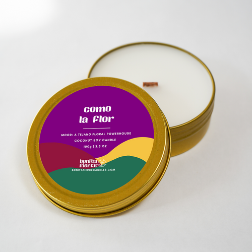 Candle in a metallic tin with colorful label on a white background