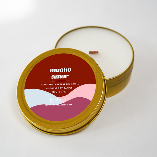 Candle in a gold tin with 'mucho amor' label on a white background