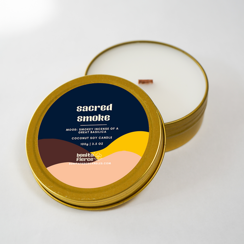 Candle in a metallic tin with 'sacred smoke' label on a white background